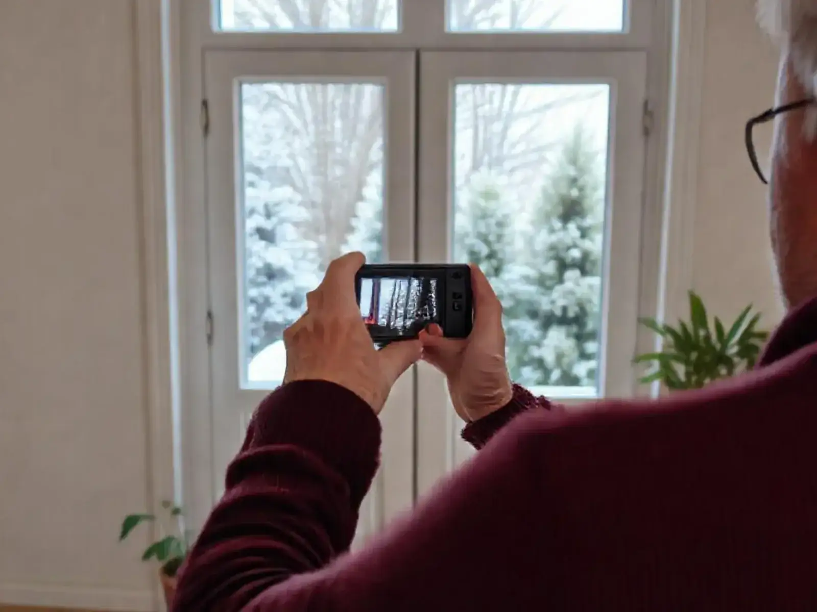 Personne photographiant une fenêtre entière avec son téléphone, à quelques pas en retrait