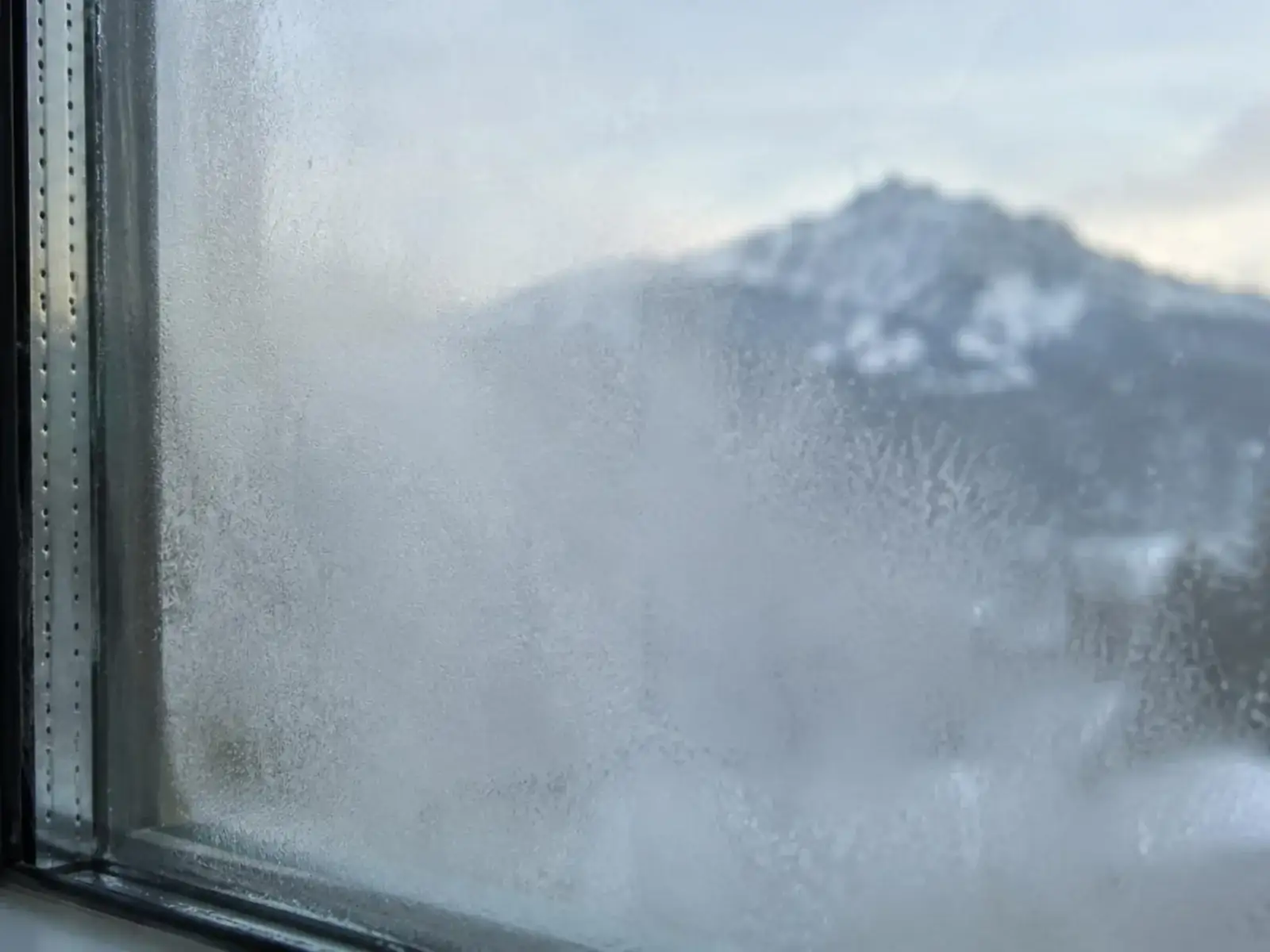 Double vitrage embué entre les deux vitres, montagnes floues derrière
