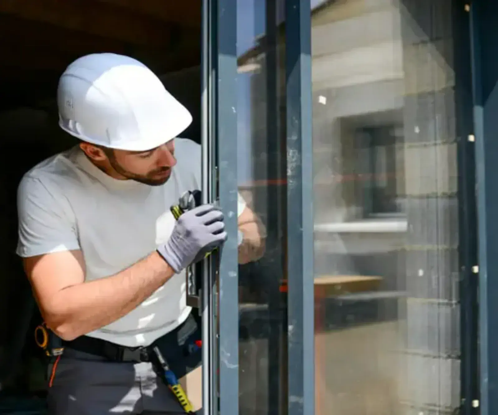 Établi en bois avec profilés aluminium, vitrages et rouleaux de joints dans un petit atelier