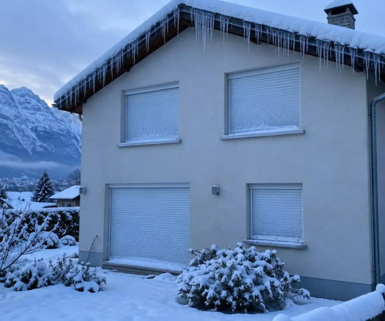 Volets roulants baissés et givrés sur une façade enneigée